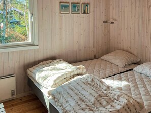 A bedroom with two beds, wooden walls, a window, and three framed pictures on the wall. - 8 Person Holiday Home in Albaek (Jerup)