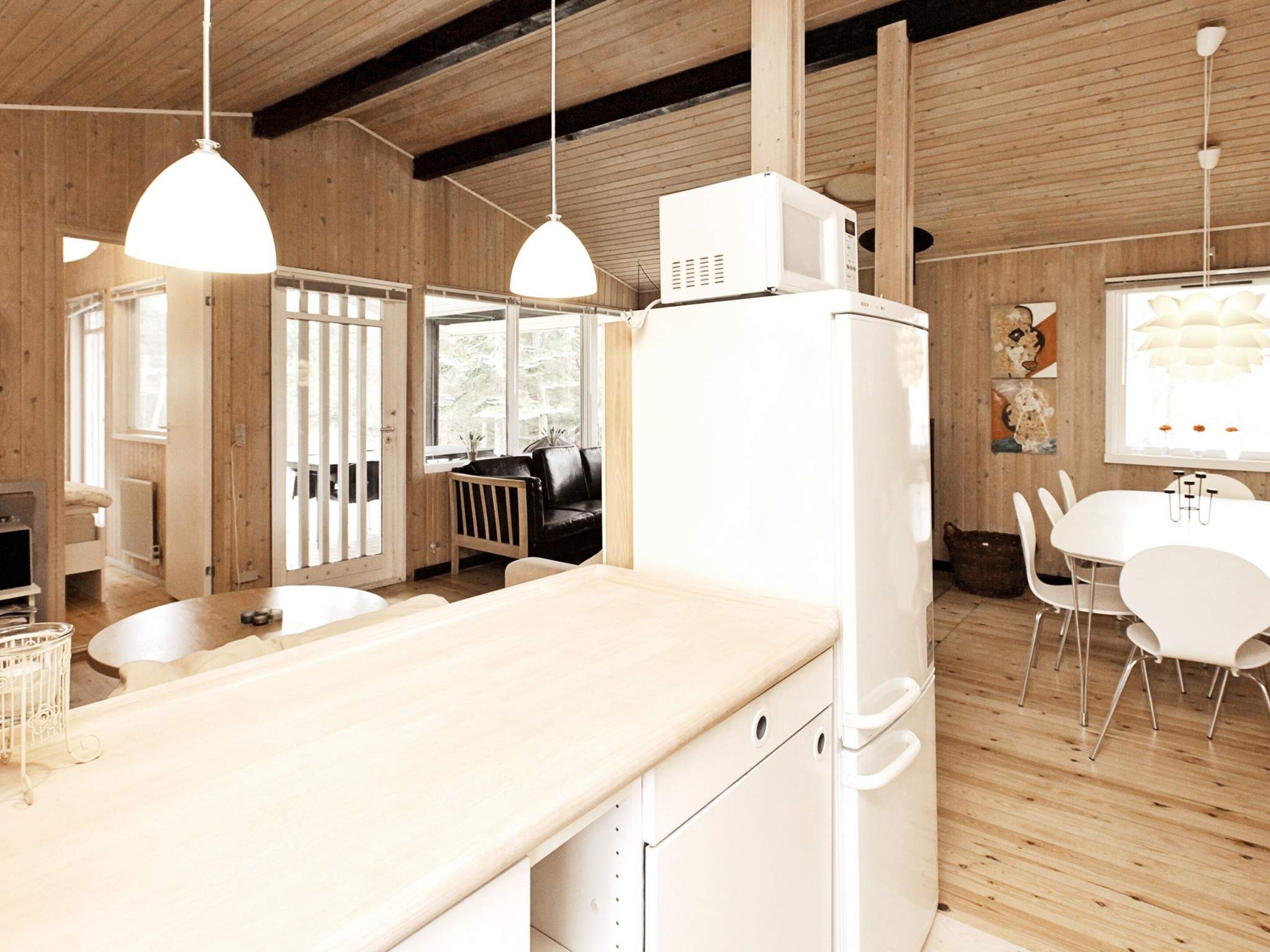 Uma cozinha moderna com paredes de madeira, eletrodomésticos brancos e iluminação pendente.