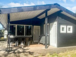 Una casa moderna con porche cubierto, ventanas amplias y una pequeña terraza.