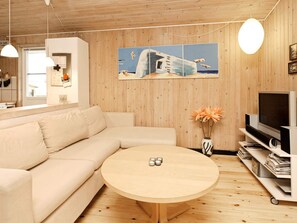 A modern living room with a beige sectional sofa, a round wooden coffee table, and a flat-screen TV on a white stand. - 8 Person Holiday Home in Albaek (Jerup)