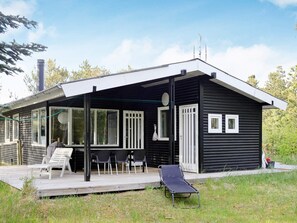 A modern black cabin with a covered patio, a lounge chair, and a small deck. - 8 Person Holiday Home in Albaek (Jerup)