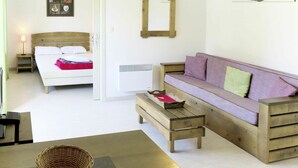 Una habitación con una cama, un banco de madera, un sofá y un espejo sujeto a la pared.