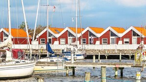 A marina with boats docked and red buildings with white trim in the background.
