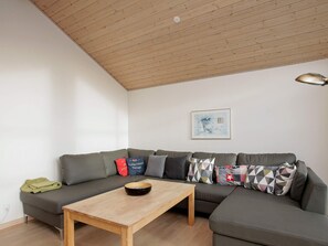 A modern living room with a wooden ceiling, a grey sofa, a wooden coffee table, and a framed picture on the wall. - 8 Person Holiday Home in Jerup (Jerup)