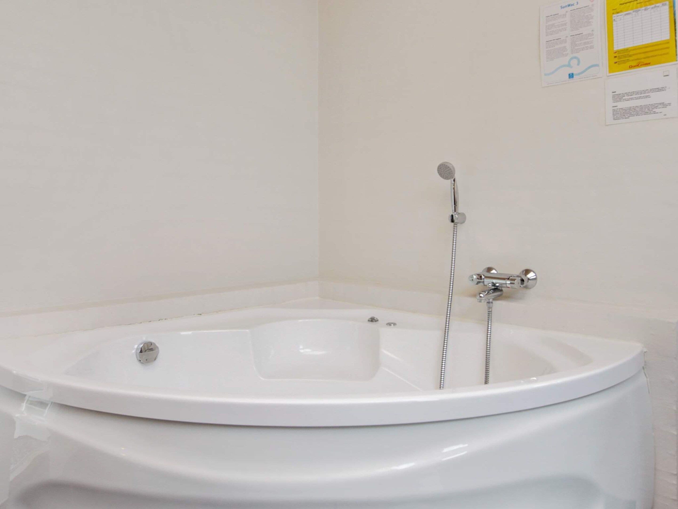 A white bathtub with a handheld showerhead and a faucet.