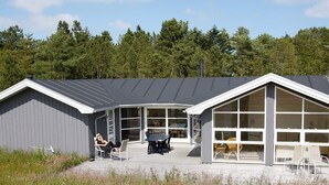 A modern building with a covered patio area, large windows, and a deck with outdoor seating. - 8 Person Holiday Home in Jerup (Jerup)