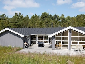 A modern building with a covered patio area, large windows, and a deck with outdoor seating. - 8 Person Holiday Home in Jerup (Jerup)