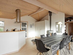 A modern interior with a long dining table, black chairs, a kitchen area, and a large window. - Luxury Retreat in Bratten (Jerup)