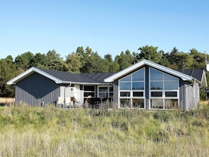 A two-story building with a large garage and a covered patio area. - 8 Person Holiday Home in Jerup (Jerup)