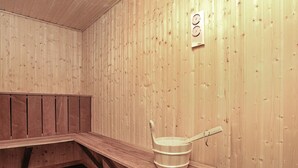 A sauna room with wooden walls, a bench, a bucket, and a heater. - 8 Person Holiday Home in Jerup (Jerup)