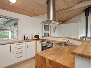 A modern kitchen with wooden countertops, stainless steel appliances, and a large window. - 8 Person Holiday Home in Jerup (Jerup)