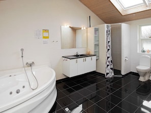 A modern bathroom with a freestanding bathtub, a sink with a mirror, and a toilet. - 8 Person Holiday Home in Jerup (Jerup)