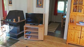 A living room with a television, a fireplace, a wooden cabinet, and a dining area.