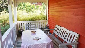 Eine überdachte Terrasse mit Tisch und Bänken, umgeben von einem Geländer.