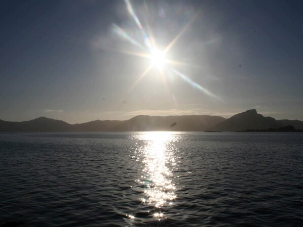 A calm body of water reflecting sunlight with mountains in the background. - Holiday Home in Ã…ram (Vanylven)