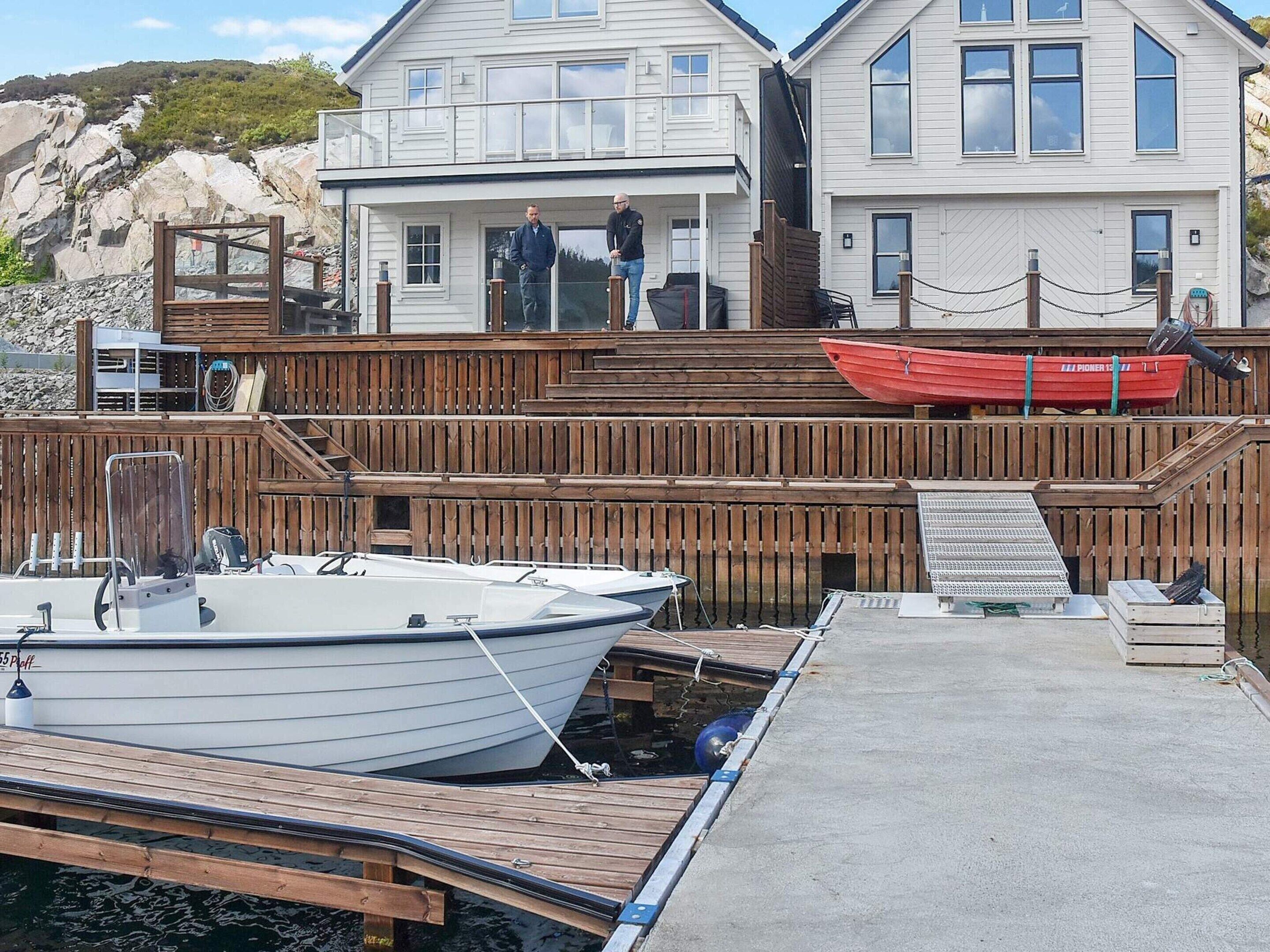 A dock with boats, a wooden deck, and a house with a balcony.