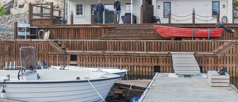 A dock with boats, a wooden deck, and a house with a balcony.