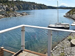A clear view of a lake with a dock, a boat, and a rocky shoreline. - 5 Star Holiday Home in Urangsvag (Bomlo)