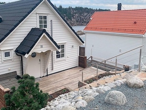 A two-story house with a wooden deck, a small porch, and a view of a rocky shoreline. - 5 Star Holiday Home in Urangsvag (Bomlo)
