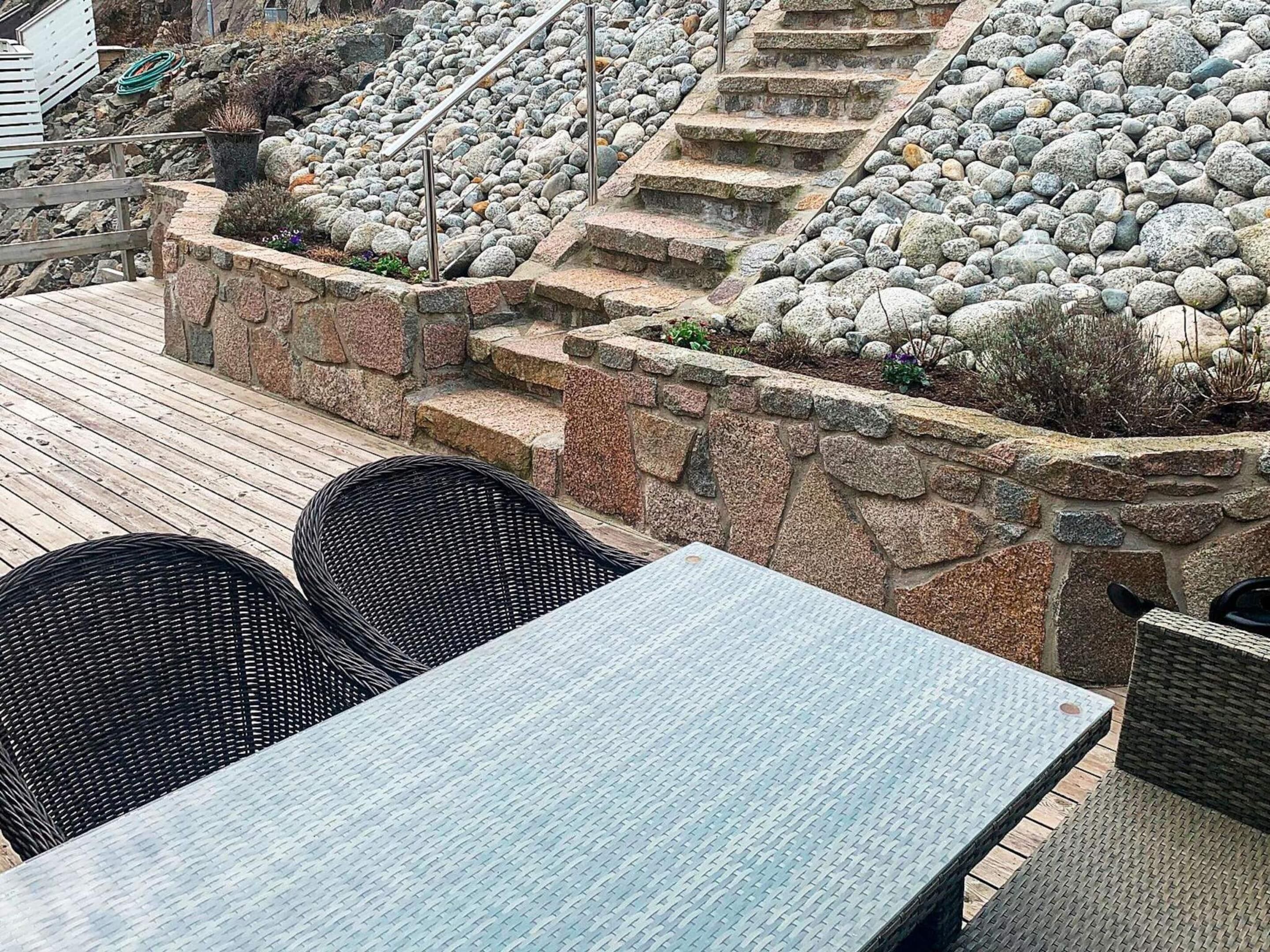 A patio with stone steps, a table, and wicker chairs.