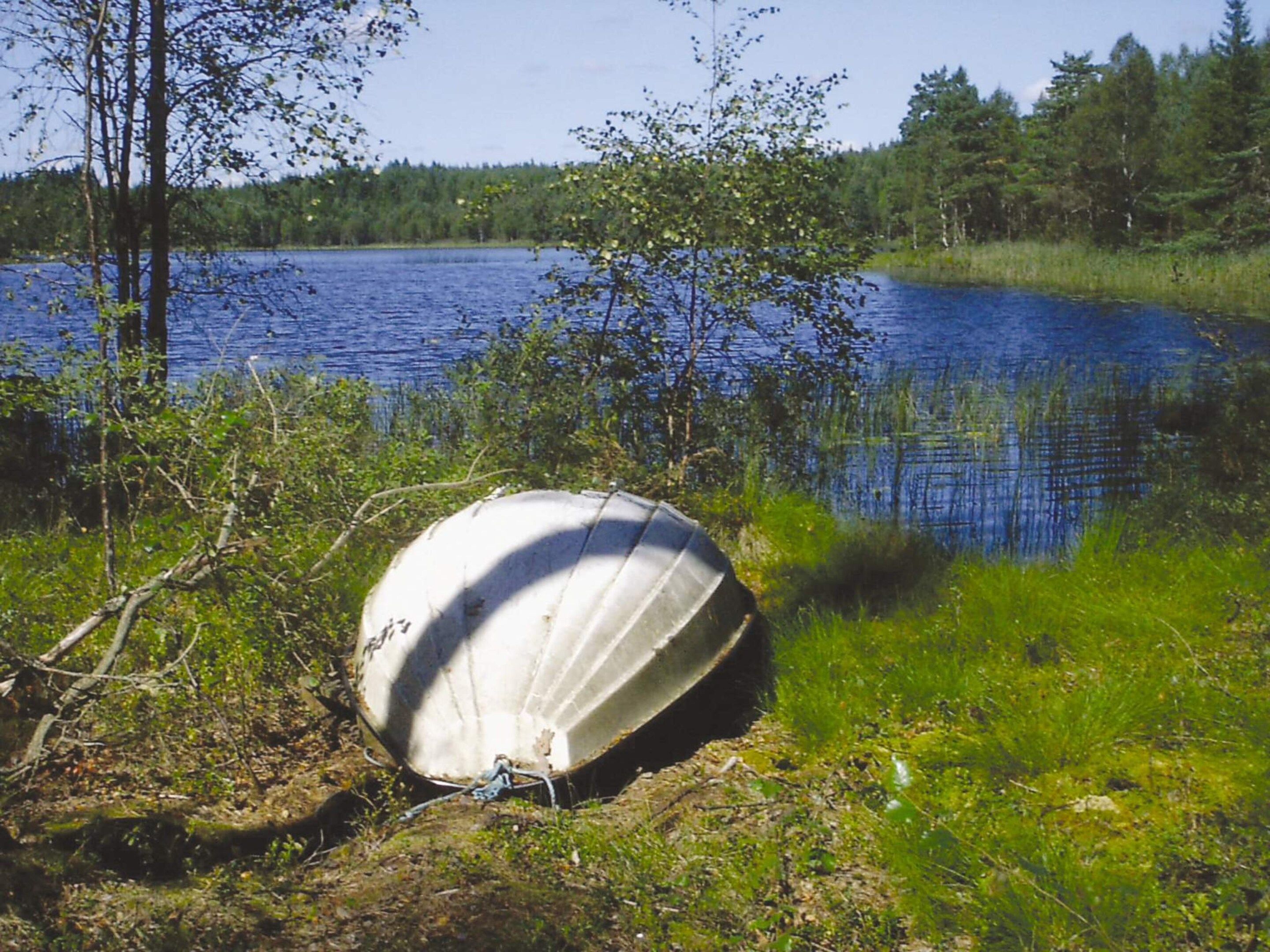 Vene on kiinnitetty laiturissa, ja laituri sijaitsee järven rannalla, jota ympäröivät puut.