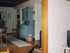 Una habitación con piso de madera, un armario azul, una cesta de mimbre y un televisor sobre un soporte.