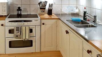 Cocina compacta con estufa, horno, pileta y encimera de madera.