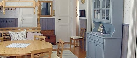 Una habitación con una mesa de comedor de madera, sillas, un armario y una alfombra a rayas.