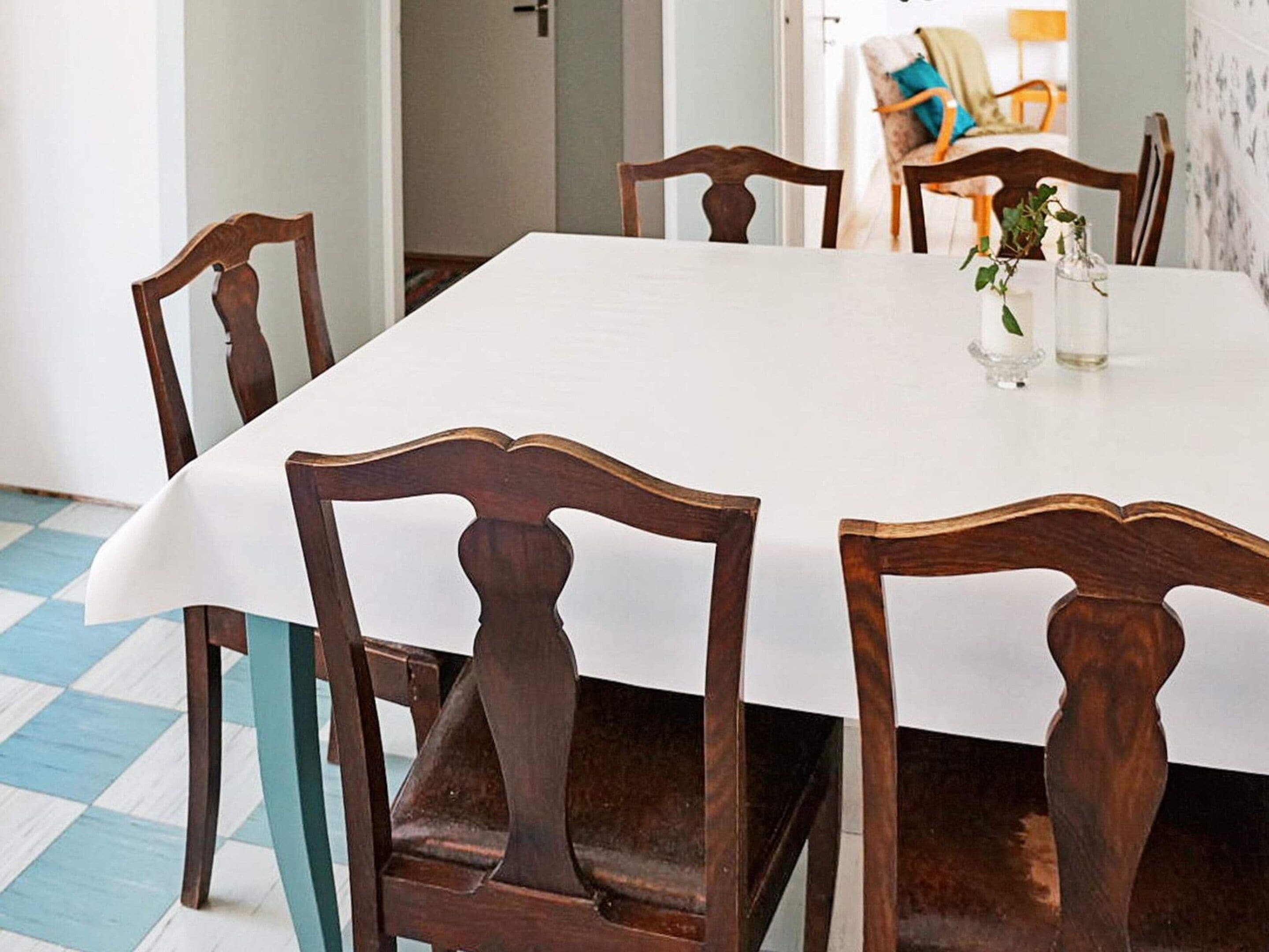 A dining area with a white table and wooden chairs.