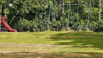A playground with a red slide and swings.