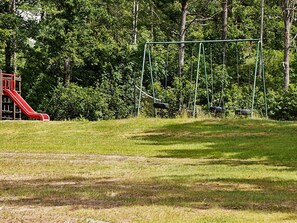 A playground with a red slide and swings. - 6 Person Holiday Home in Odensvi (Gamleby)