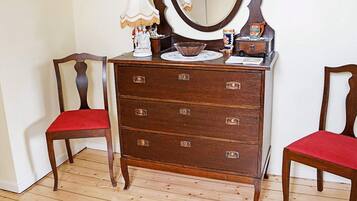 A wooden dresser with four drawers, a mirror, and a lamp.