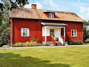 A red wooden house with a tiled roof, a small porch, and a visible window. - 6 Person Holiday Home in Odensvi (Gamleby)