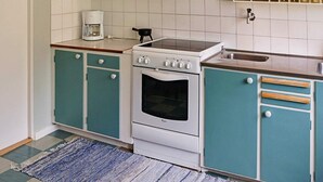 A kitchen with teal cabinets, a white stove, and a coffee maker.