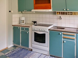 A kitchen with teal cabinets, a white stove, and a coffee maker. - 6 Person Holiday Home in Odensvi (Gamleby)