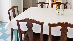A dining table with a white tablecloth, surrounded by wooden chairs with curved backs.
