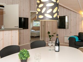 Una habitación compacta con una mesa de comedor, sillas, televisor, cama y una planta en maceta.