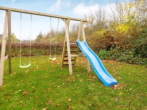 Ein hölzerner Schaukelrahmen mit einer blauen Rutsche auf einem Rasen.