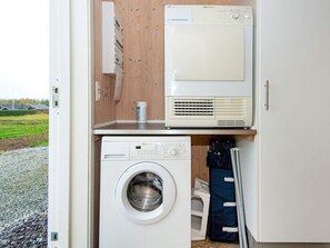 A laundry room with a washing machine and a dryer, wooden walls, and a view of a green field. - 4 Star Holiday Home in Sydals (Sydals)