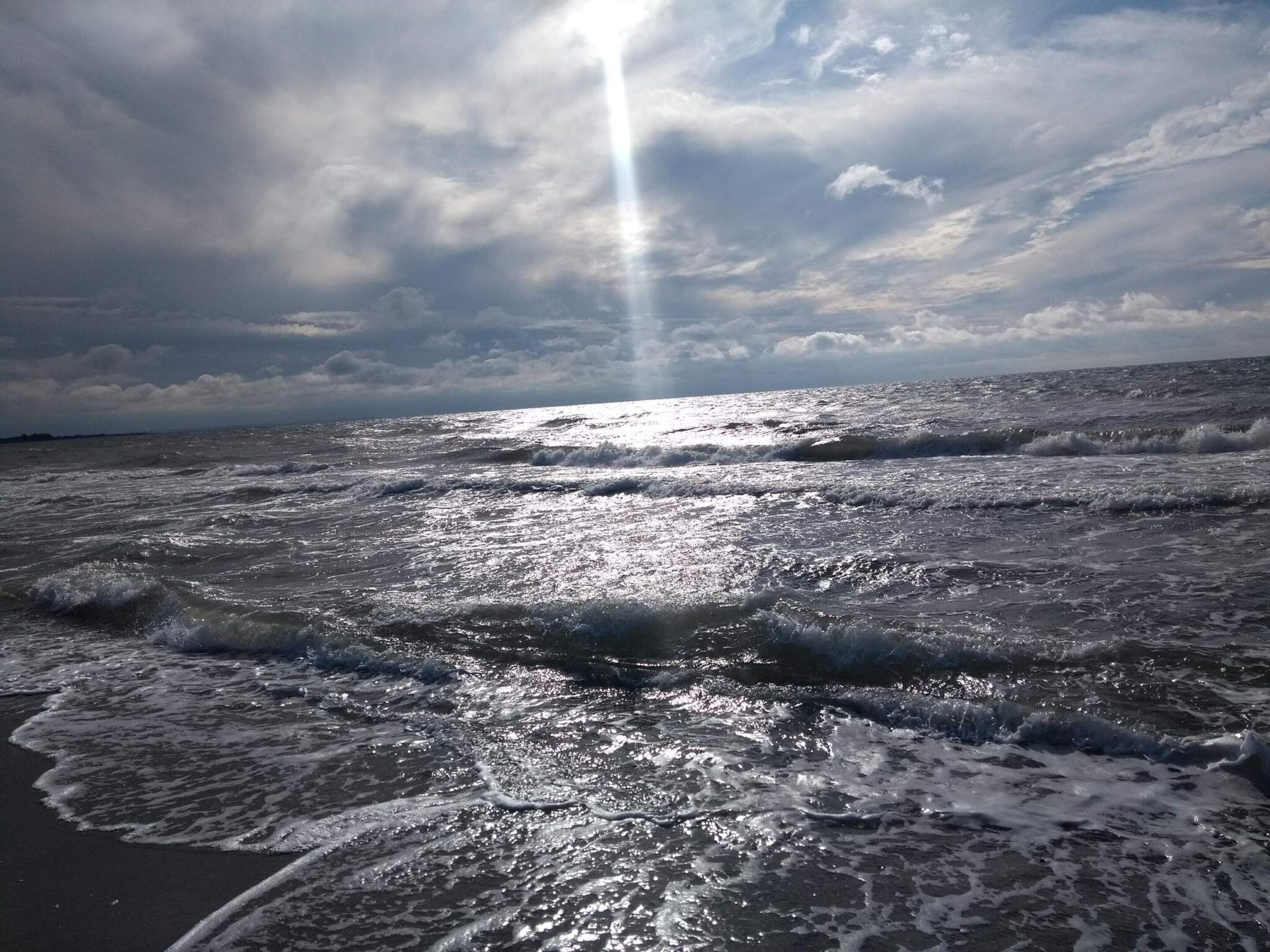 Ein Strand mit Wellen und einem bewölkten Himmel.