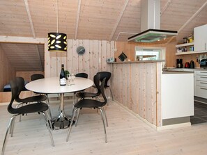 A modern kitchen with wooden walls, a round dining table, and black chairs.