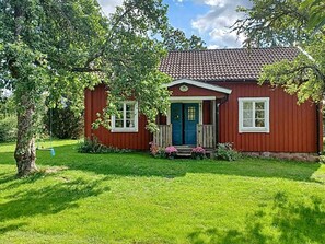 A red wooden house with a blue door, white windows, and a porch with steps. - 6 Person Holiday Home in Alsterbro (Alsterbro)