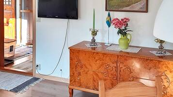 A room with a wooden cabinet, a television mounted on the wall, a painting, and a flag.