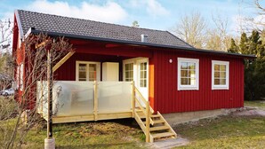Une maison en bois rouge, dotée d’un petit porche et d’un escalier en bois menant à la porte.