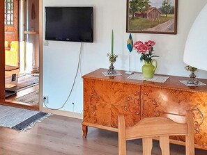 A room with a wooden cabinet, a television mounted on the wall, a painting, and a flag. - 6 Person Holiday Home in Alsterbro (Alsterbro)