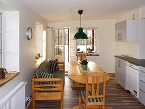 Una cocina acogedora con una mesa de madera, sillas y una lámpara colgante.