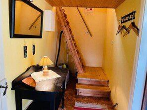 A compact room with a wooden staircase, a small table with a lamp, and a mirror on the wall. - 4 Person Holiday Home in Skruv (Skruv)