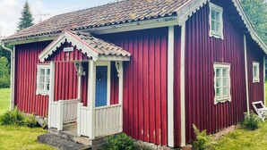 A red wooden house with a white porch and a blue door. - 4 Person Holiday Home in Skruv (Skruv)