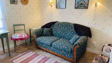 A cozy living room with a patterned sofa, a small table, a chair, and a decorative rug.