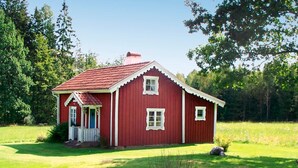 A red wooden house with a white porch and a small front yard. - 4 Person Holiday Home in Skruv (Skruv)